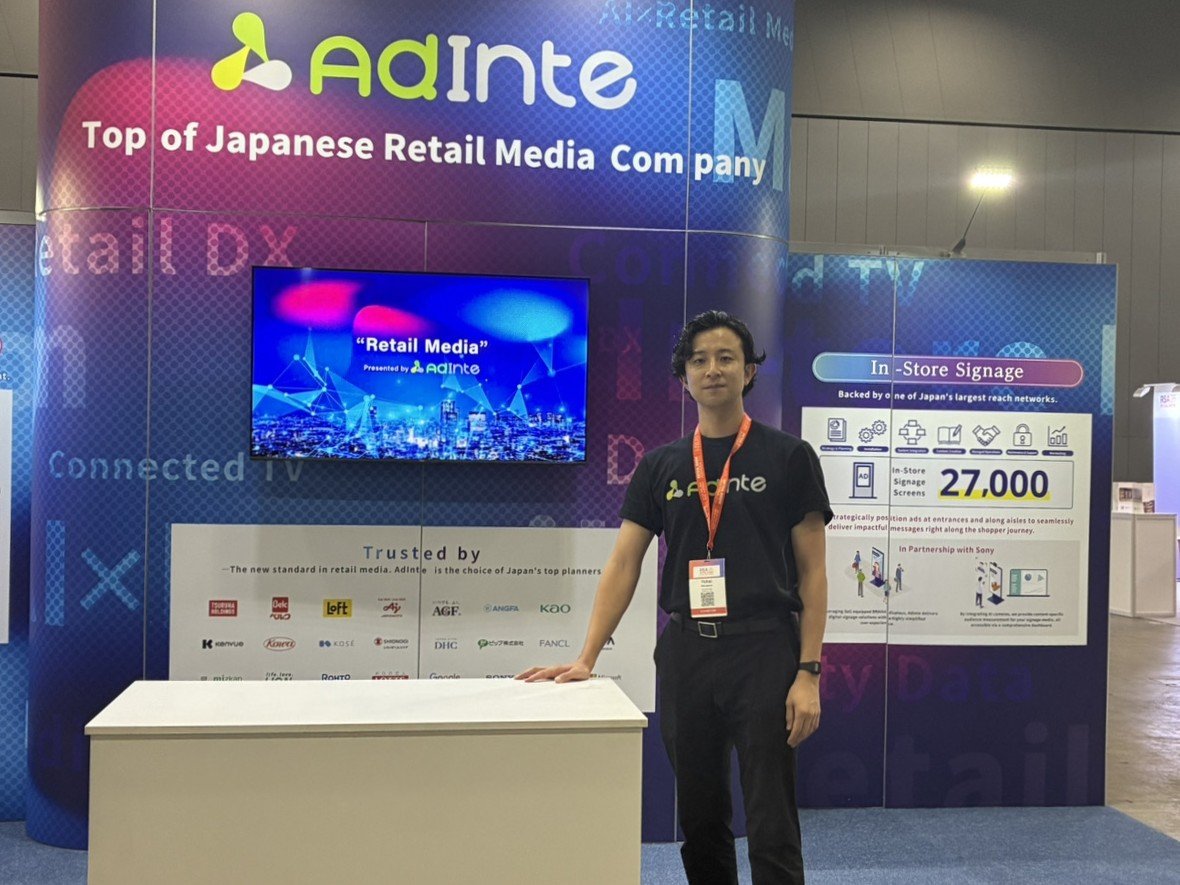 株式会社アドインテの展示ブースの前に立つ丸山さん