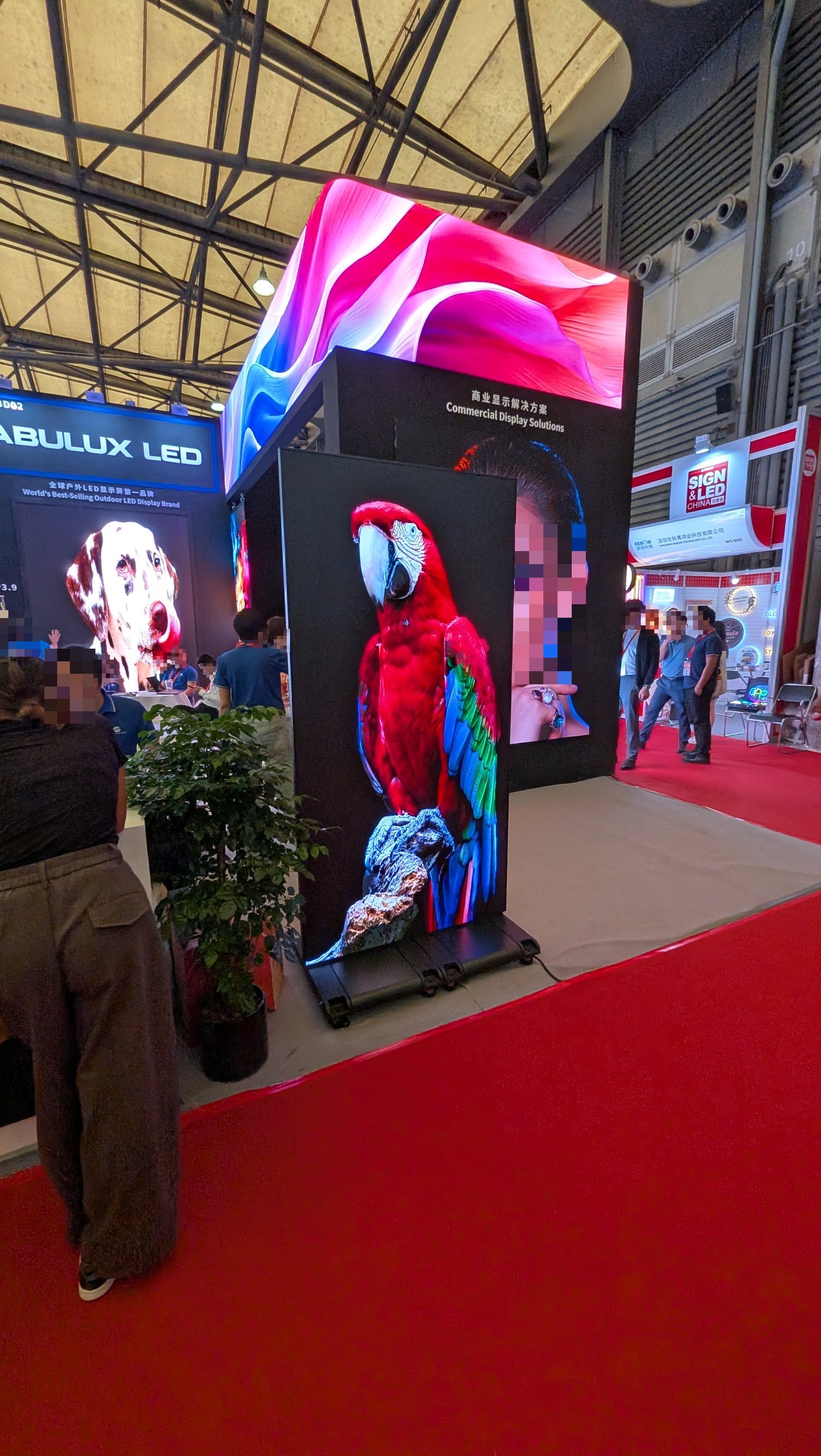 展示会ブースに設置された、オウムの映像を映す縦型LEDディスプレイ