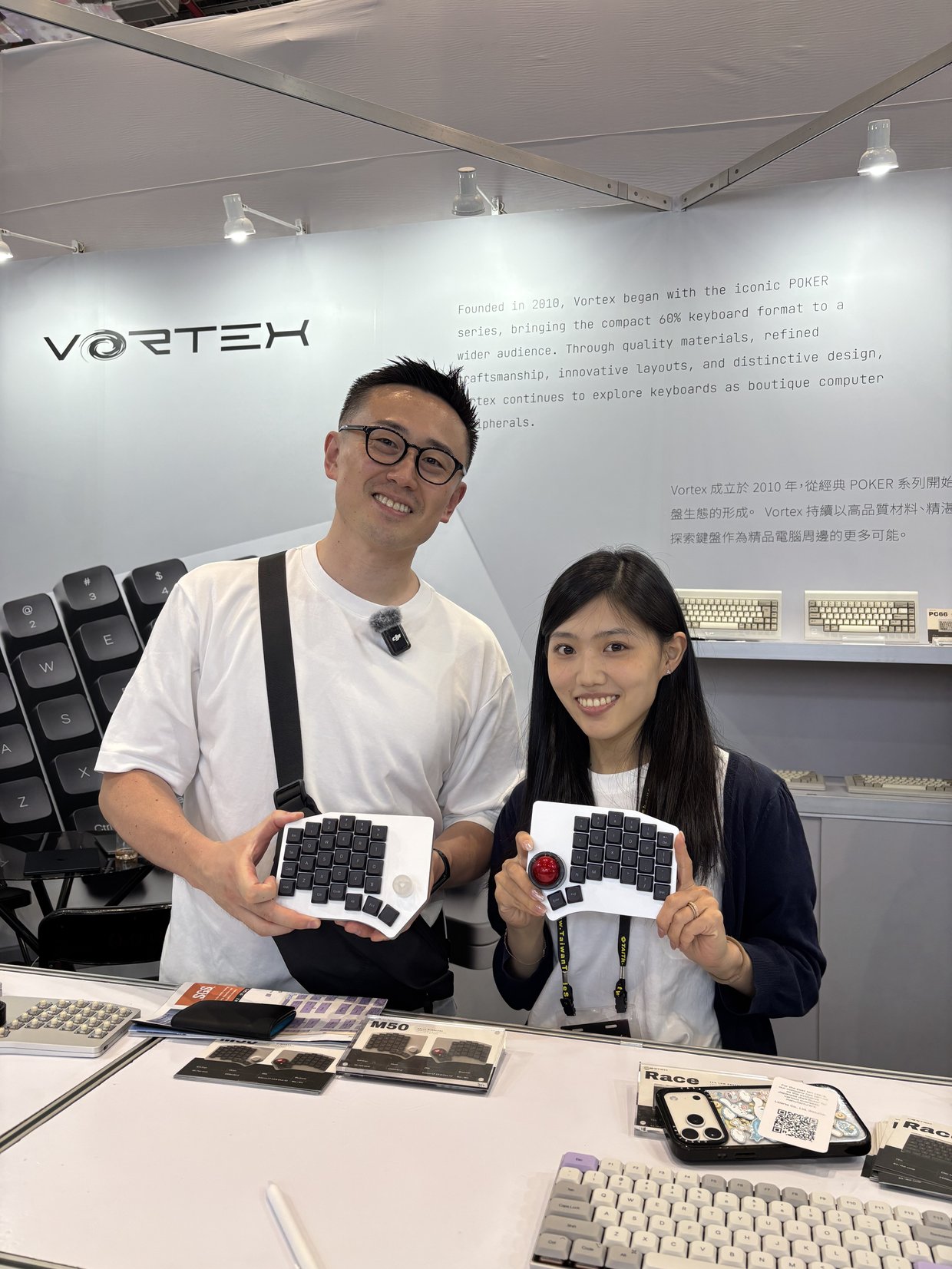 キーボードメーカーのブースで、製品を手にする高村さんとブースの担当者